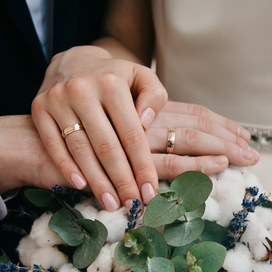 Couple wearing matching yellow gold matching his and hers wedding bands