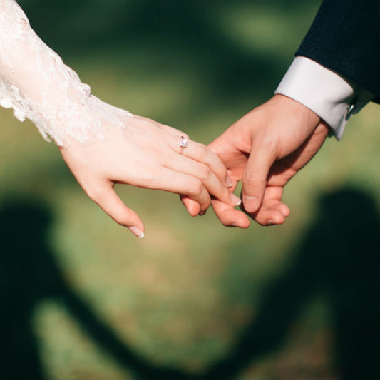 bride wearing simple rose gold engagement ring holding groom's hand