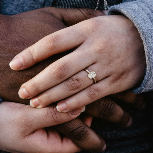 couple holding hands woman wearing oval solitaire engagement ring