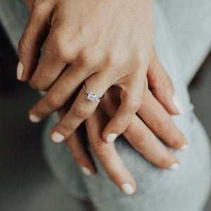 womans hands wearing emerald cut engagement ring
