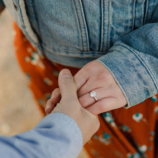 man holding woman's hand wearing 6 prong round engagement ring