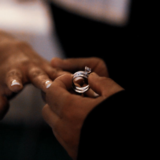 man sliding traditional engagement ring on woman's finger