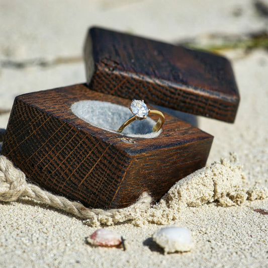 oval engagement ring in box on the beach