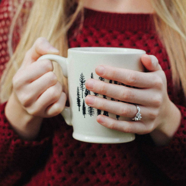 woman holding coffee cup wearing either emerald or radiant