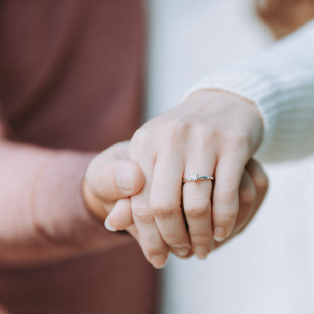 woman holding out hand wearing diamond engagement ring