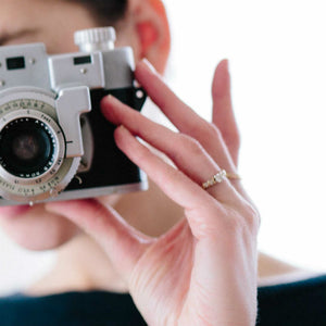 woman wearing antique style engagement ring holding camera