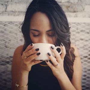 woman wearing engagement ring sipping from cup